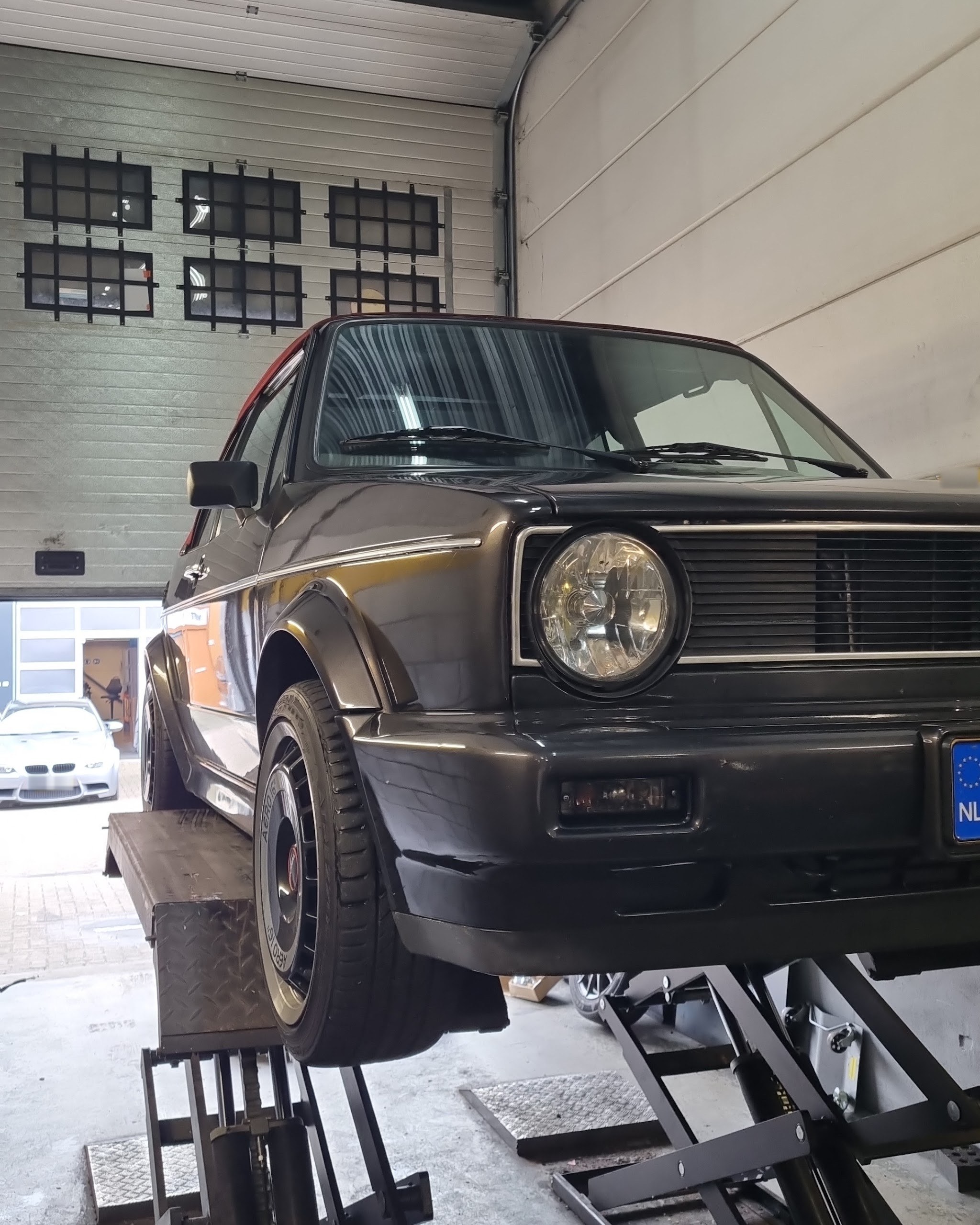 Verlaagde zwarte Volkswagen Golf op de brug in de werkplaats