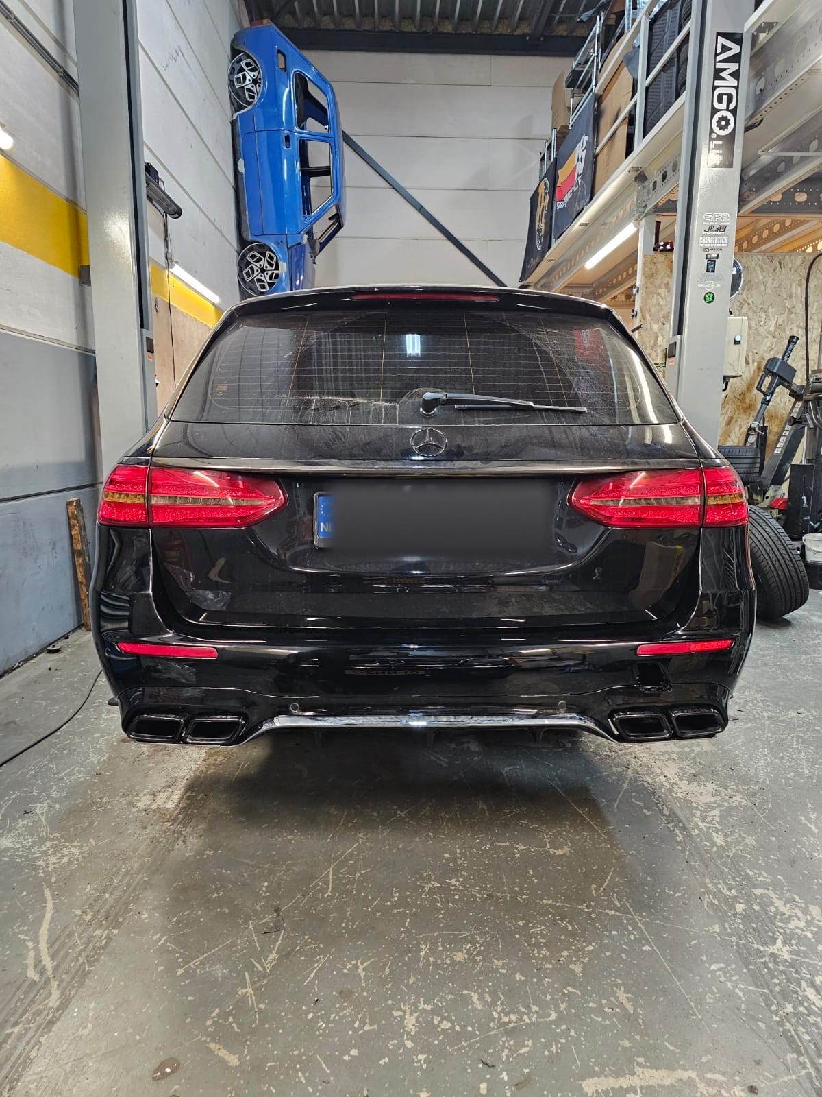 Achterkant van een zwarte Mercedes stationwagen in de werkplaats